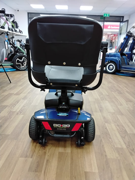 Rear view of a blue Pride Go Go Elite Traveller mobility scooter on wooden floor indoors