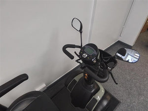 Close-up of the refurbished Excel Evo green scooter dashboard and handlebars with side mirrors indoors on carpet floor.