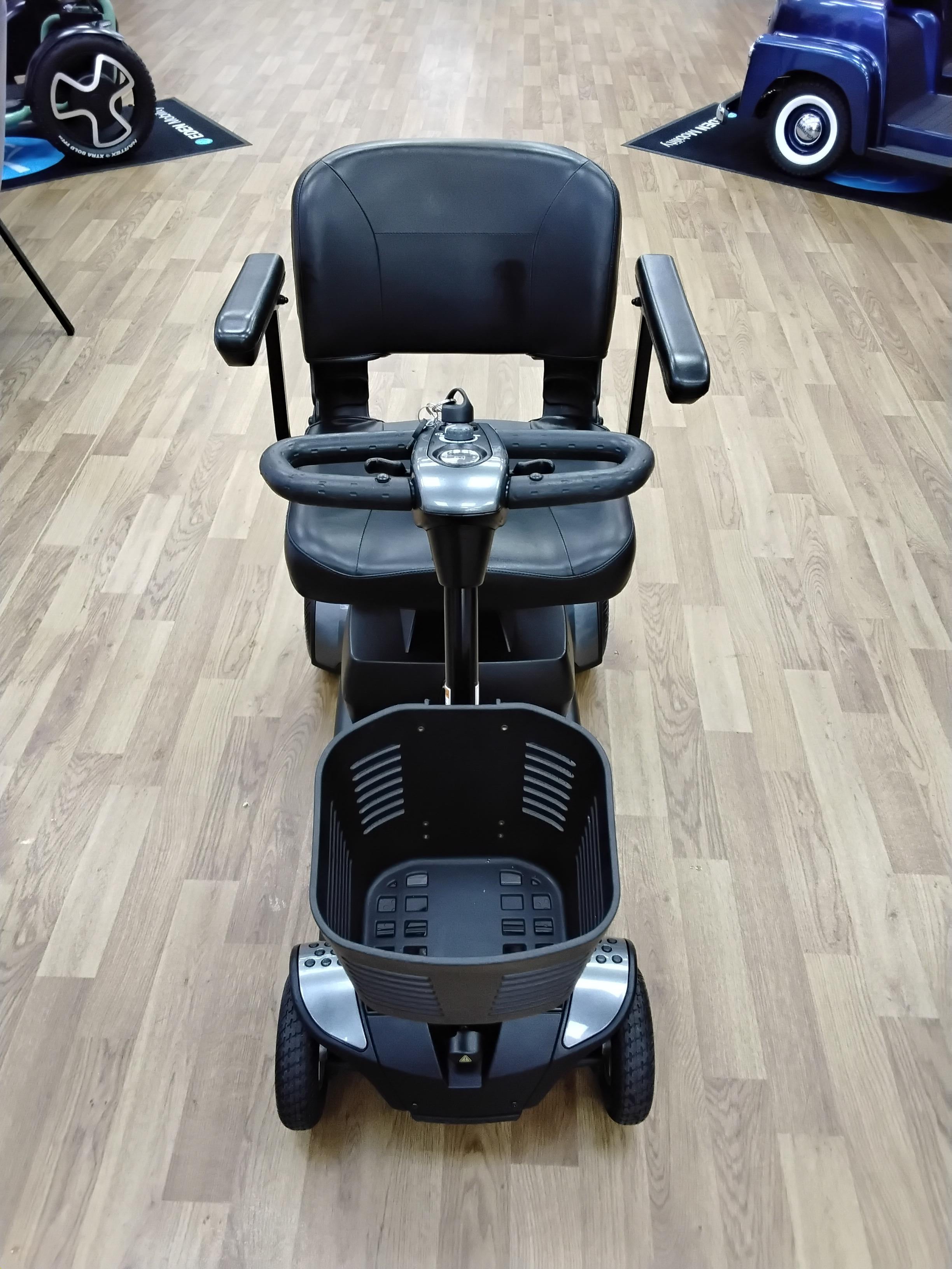 Front view of a refurbished grey Pride Go Go Elite Traveller mobility scooter with black seat and basket on wooden floor