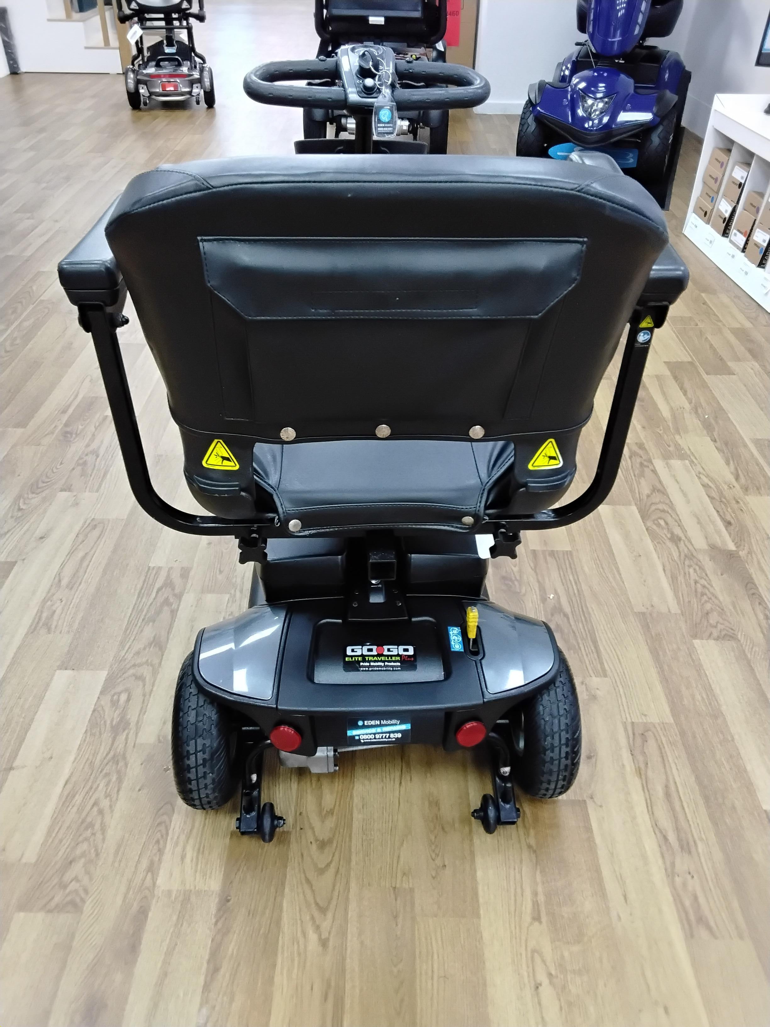 Rear view of a refurbished Pride Go Go Elite Traveller mobility scooter in grey on a wooden floor indoors