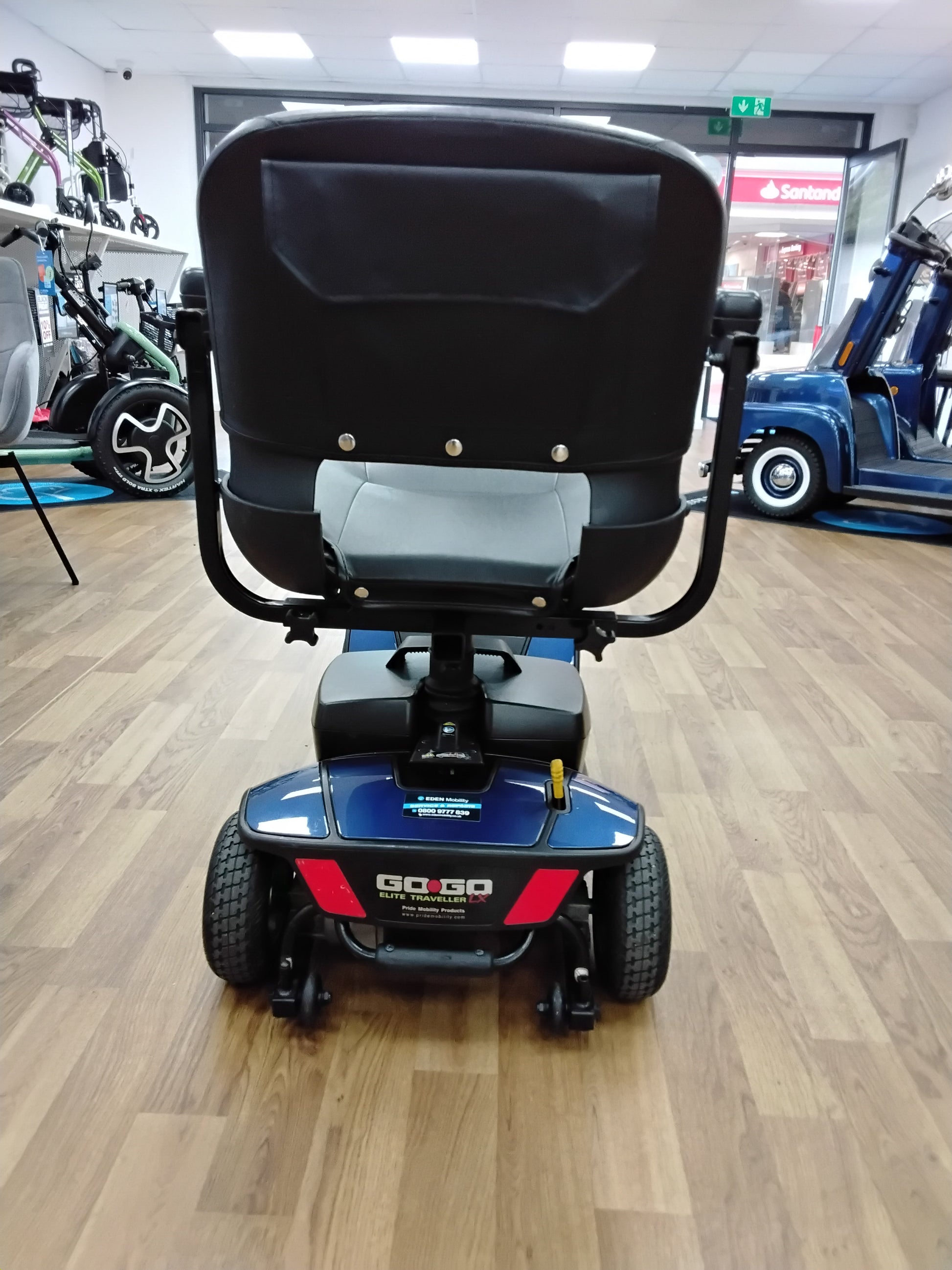Rear view of a blue Pride Go Go Elite Traveller mobility scooter on wooden floor indoors