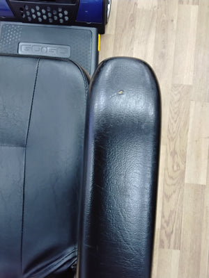 Close-up of black leather armrest and seat of a refurbished Pride Go Go Elite Traveller scooter on wooden floor.