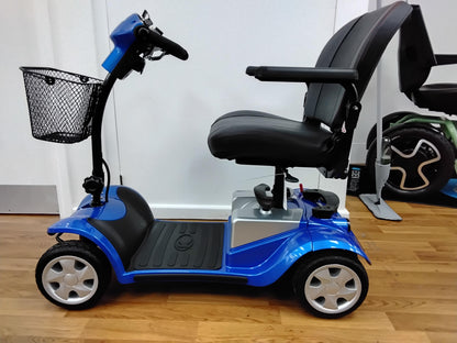 Blue Kymco Mini Comfort mobility scooter with black seat and front basket on wood floor indoors