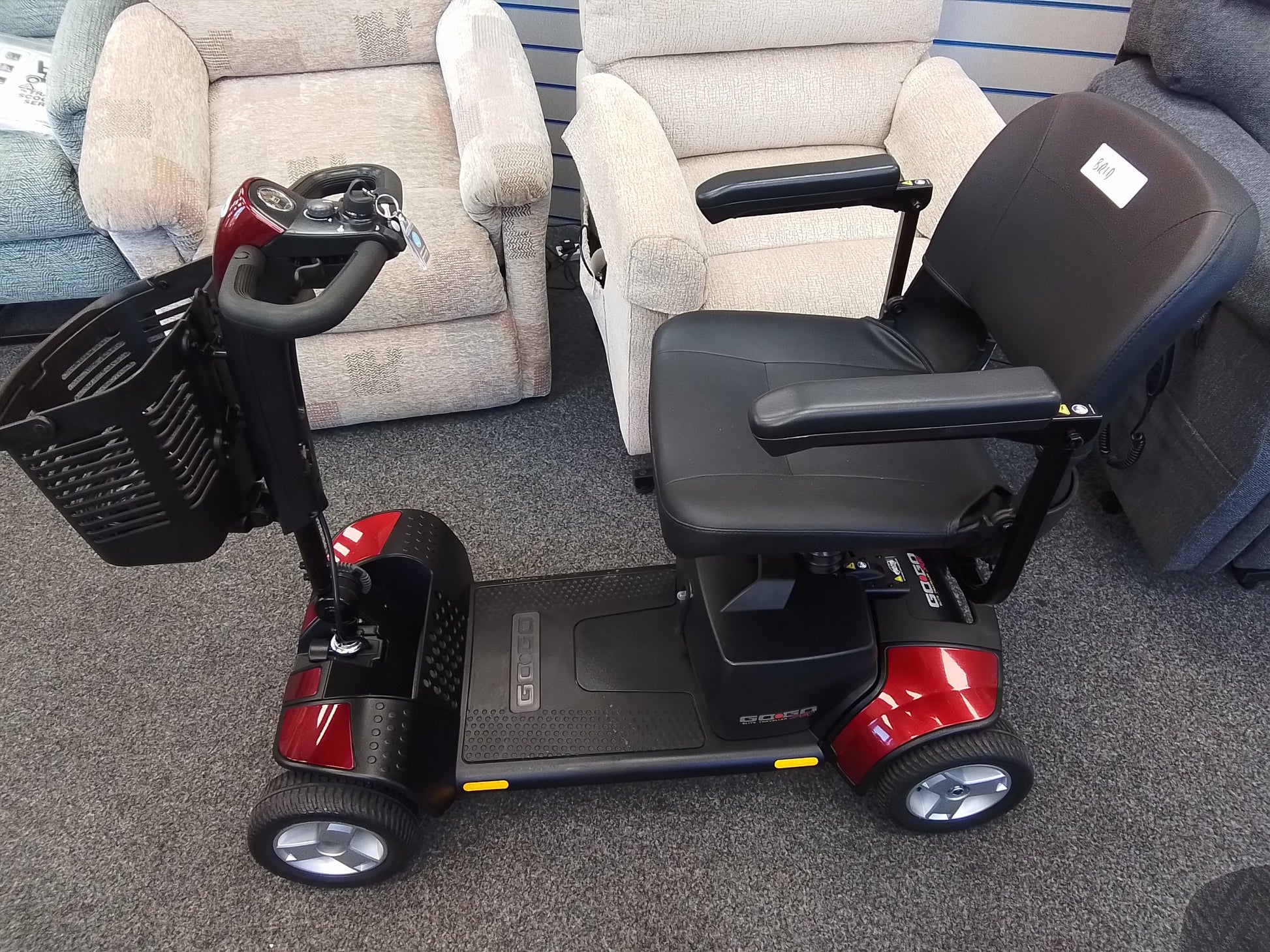 Red Pride Go Go Elite Traveller mobility scooter with black seat and basket on gray carpet indoors