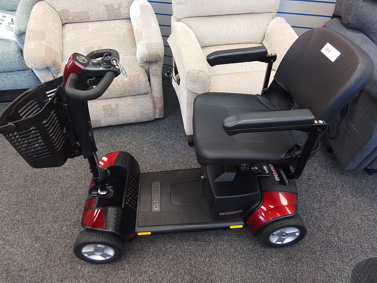 Red Pride Go Go Elite Traveller mobility scooter with black seat and basket on gray carpet indoors