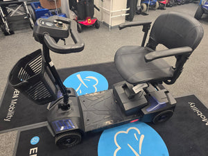 Refurbished Drive Scout Blue mobility scooter with padded seat, armrests, and storage basket on black showroom floor.
