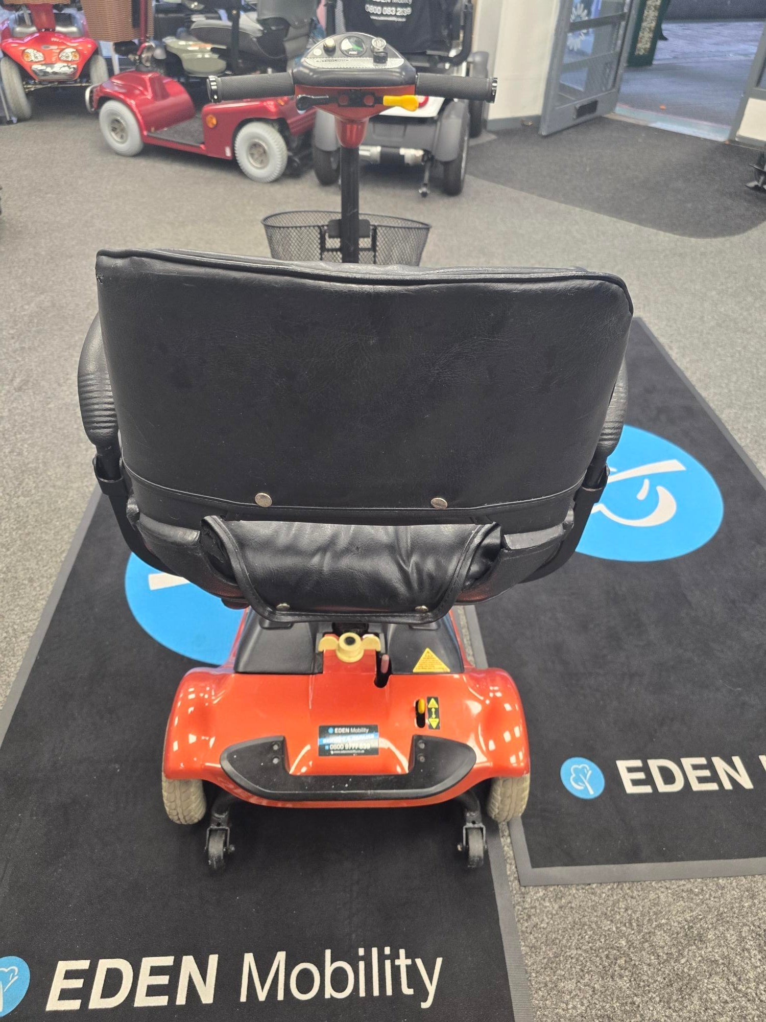 Rear view of a refurbished orange Electric Mobility Ultralite 480 scooter on Eden Mobility showroom floor