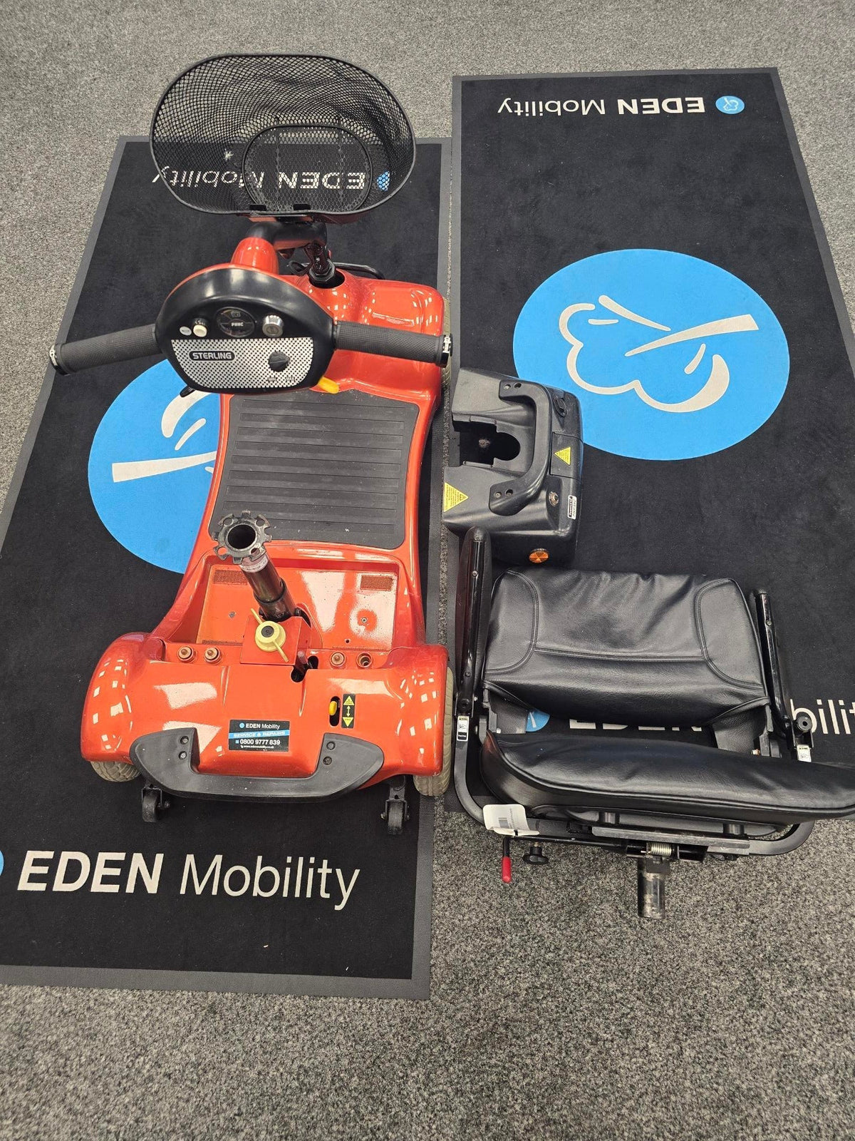 Top view of disassembled orange Electric Mobility Ultralite 480 scooter on Eden Mobility mat