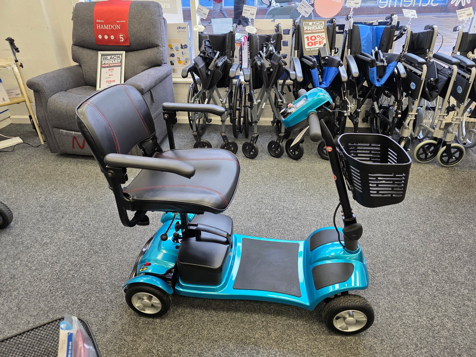 Refurbished Li-tech Air Blue mobility scooter with new batteries displayed in a store with wheelchairs and chairs in background