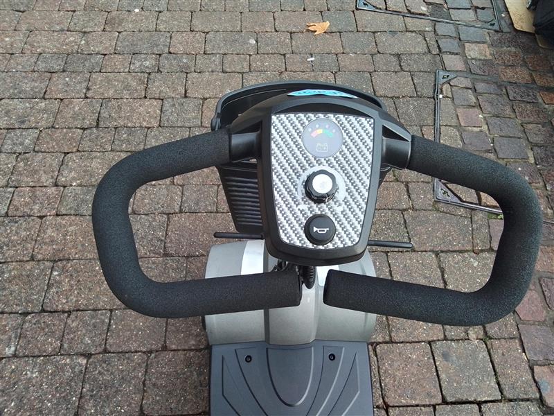 Handlebar and control panel of a refurbished grey Rascal Veo Sport mobility scooter on a brick pavement