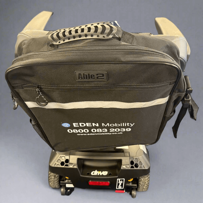 Black Eden mobility scooter with a bag attached on a Grey floor.