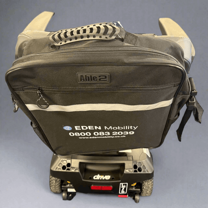 Black Eden mobility scooter with a bag attached on a Grey floor.