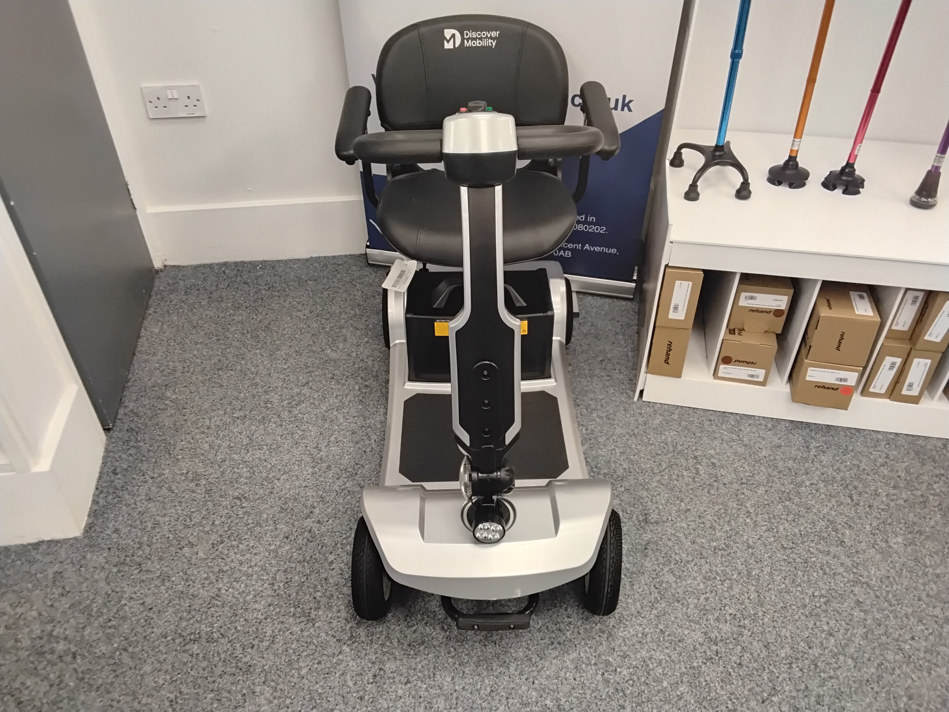 Front view of a refurbished silver Cruise Rider scooter with black seat on grey carpet indoors