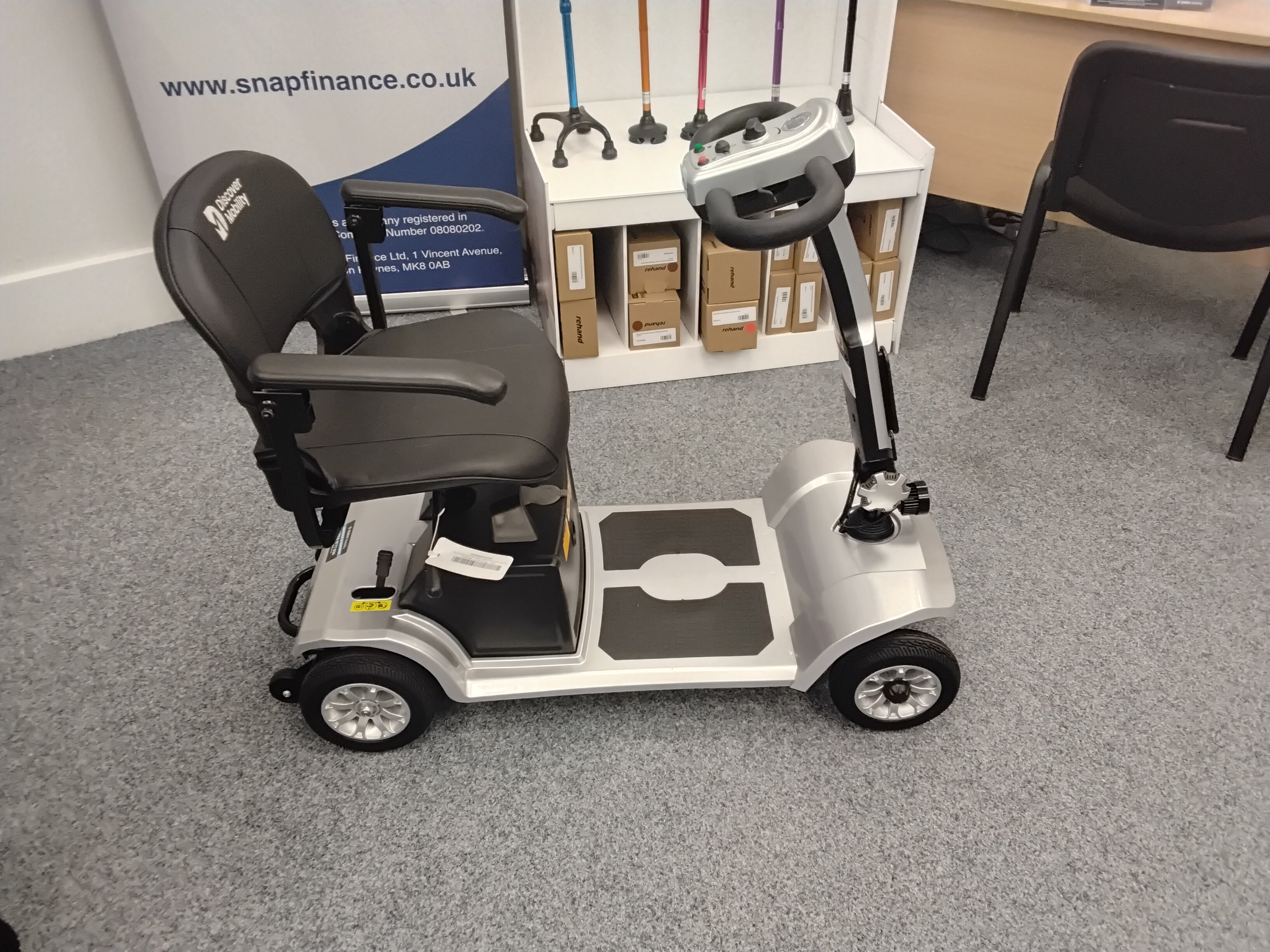 Silver Cruise Rider mobility scooter with comfortable black seat and four wheels on office carpet floor