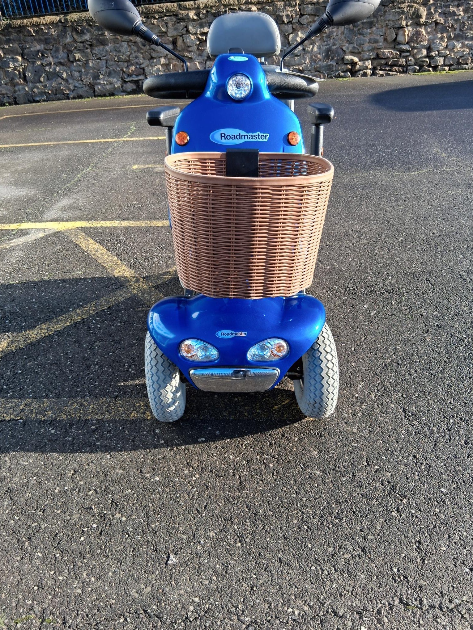 Front view of a refurbished blue Roma Shoprider Cadiz mobility scooter with a brown front basket parked outdoors