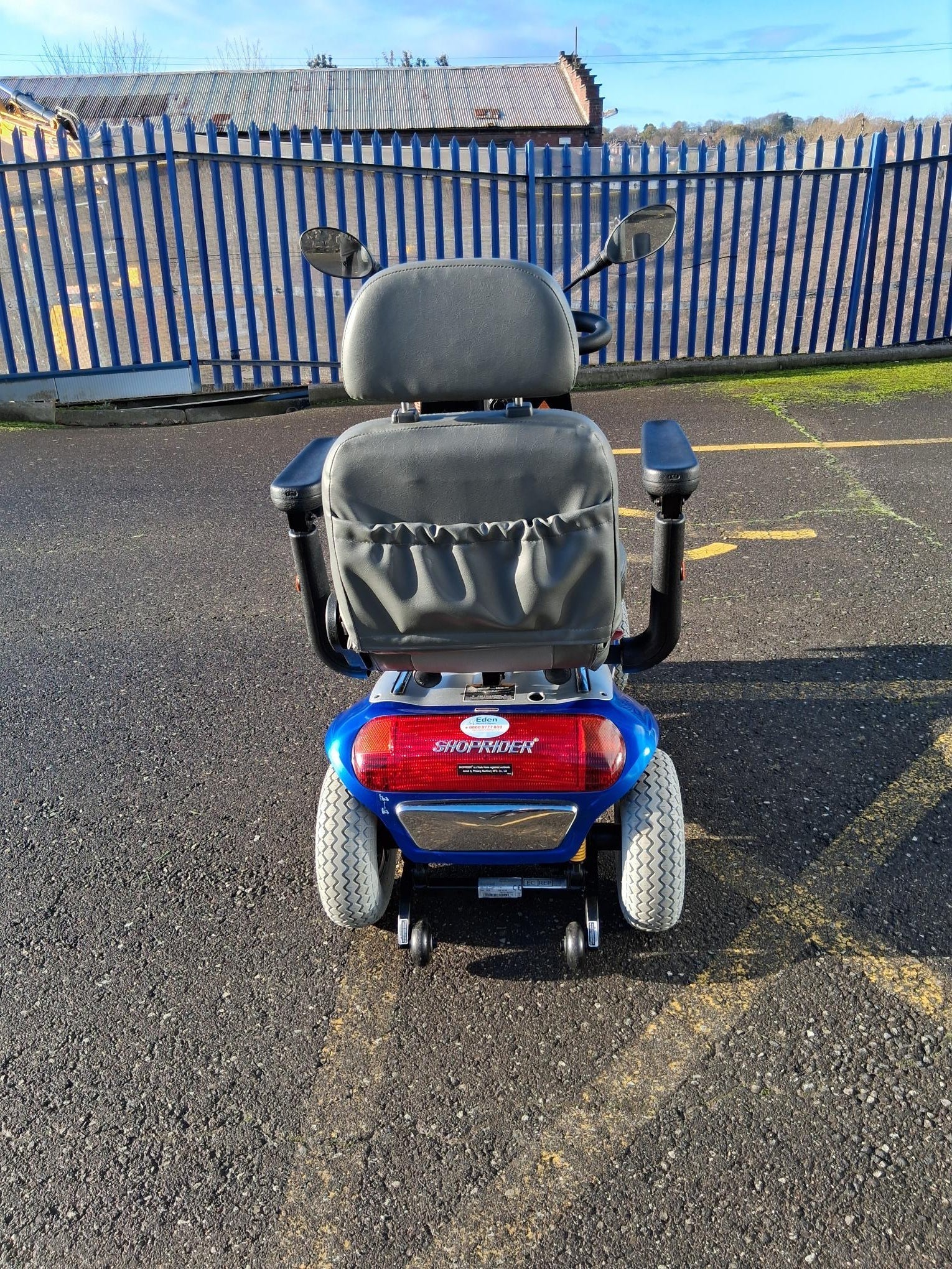 Rear view of a refurbished blue Roma Shoprider Cadiz mobility scooter parked on asphalt outdoors