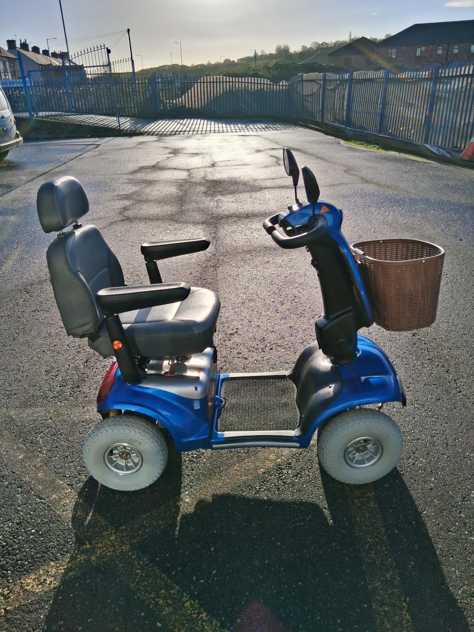 Blue Roma Shoprider Cadiz mobility scooter with black seat and front basket parked on asphalt outdoors