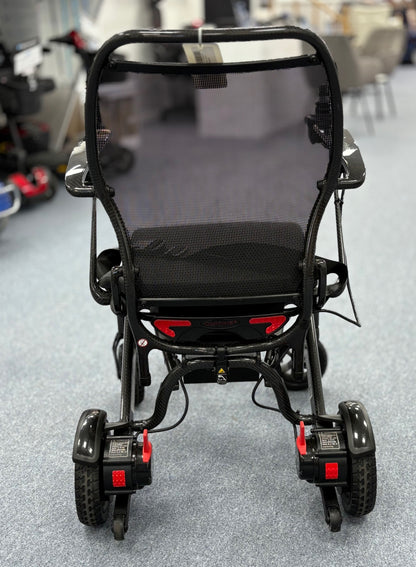 Rear view of a refurbished black Quickie Q50 R Carbon powerchair on a showroom floor with visible rear wheels and frame details