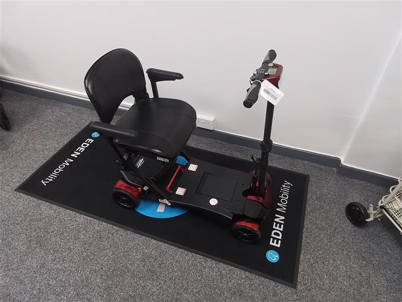 Refurbished red Drive Auto Fold scooter with black seat displayed on Eden Mobility mat indoors