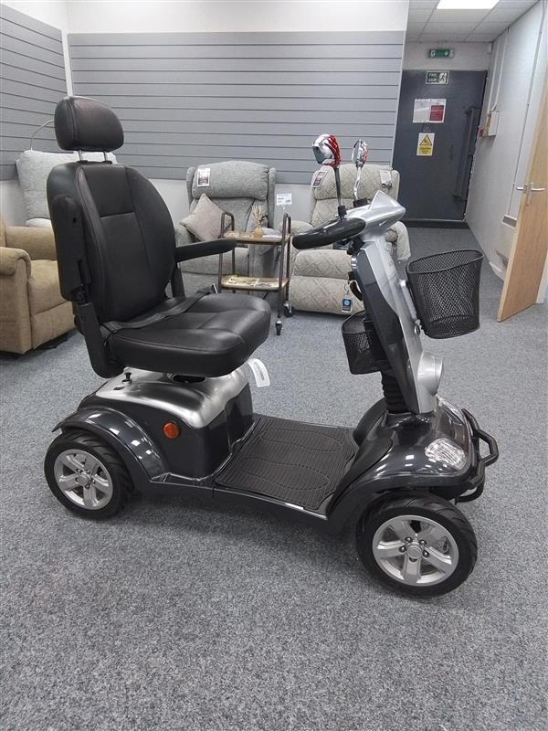 Kymco Maxi XLS grey mobility scooter with padded seat and front basket displayed indoors on carpet floor