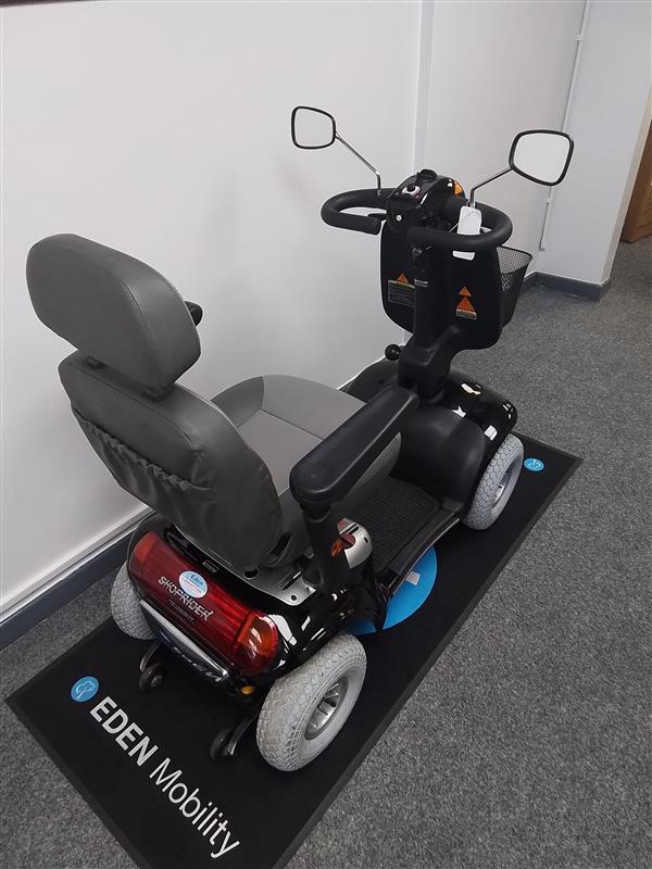 Refurbished Roma Shoprider Cadiz mobility scooter in black with comfortable seat and rear basket shown indoors on display mat.
