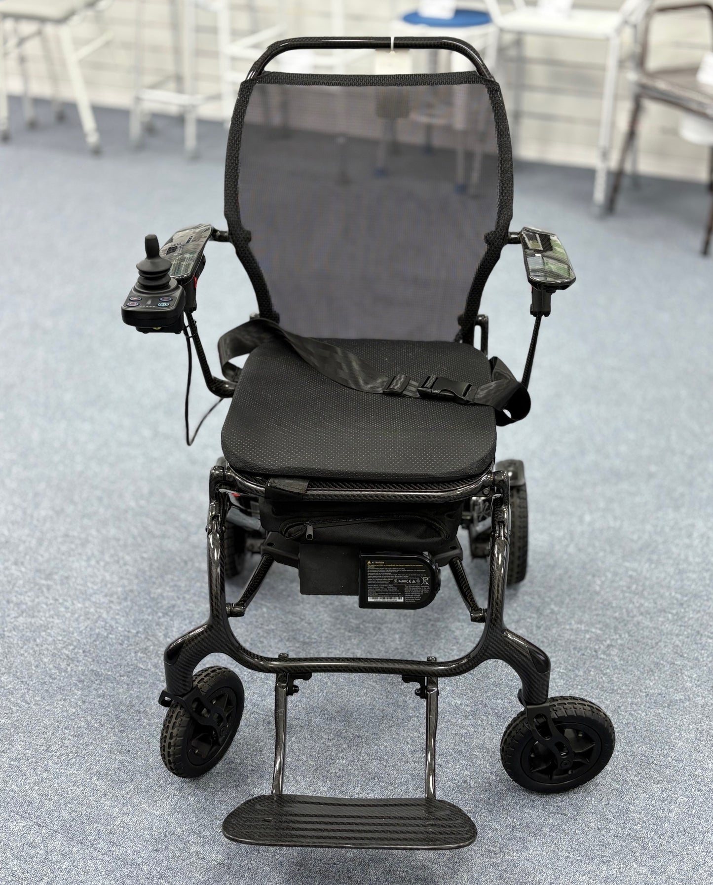 Refurbished Sunrise Medical Quickie Q50 R Carbon powerchair in black with joystick controls and mesh backrest on carpeted floor.