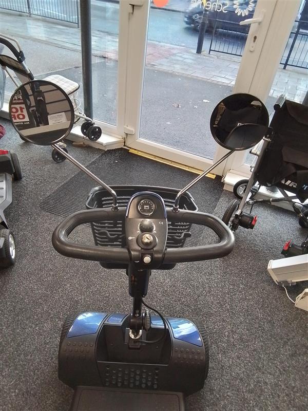 Front view of a refurbished Pride Go Go Elite Traveller mobility scooter in blue inside a showroom.