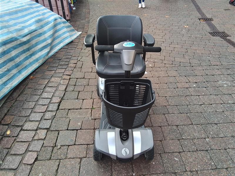 Front view of refurbished grey Rascal Veo Sport mobility scooter with black basket on cobblestone path