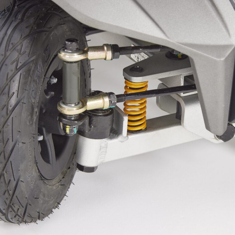 Close-up of front wheel and suspension system of Eden Essential Aura 4mph boot mobility scooter with black tire and yellow spring coil
