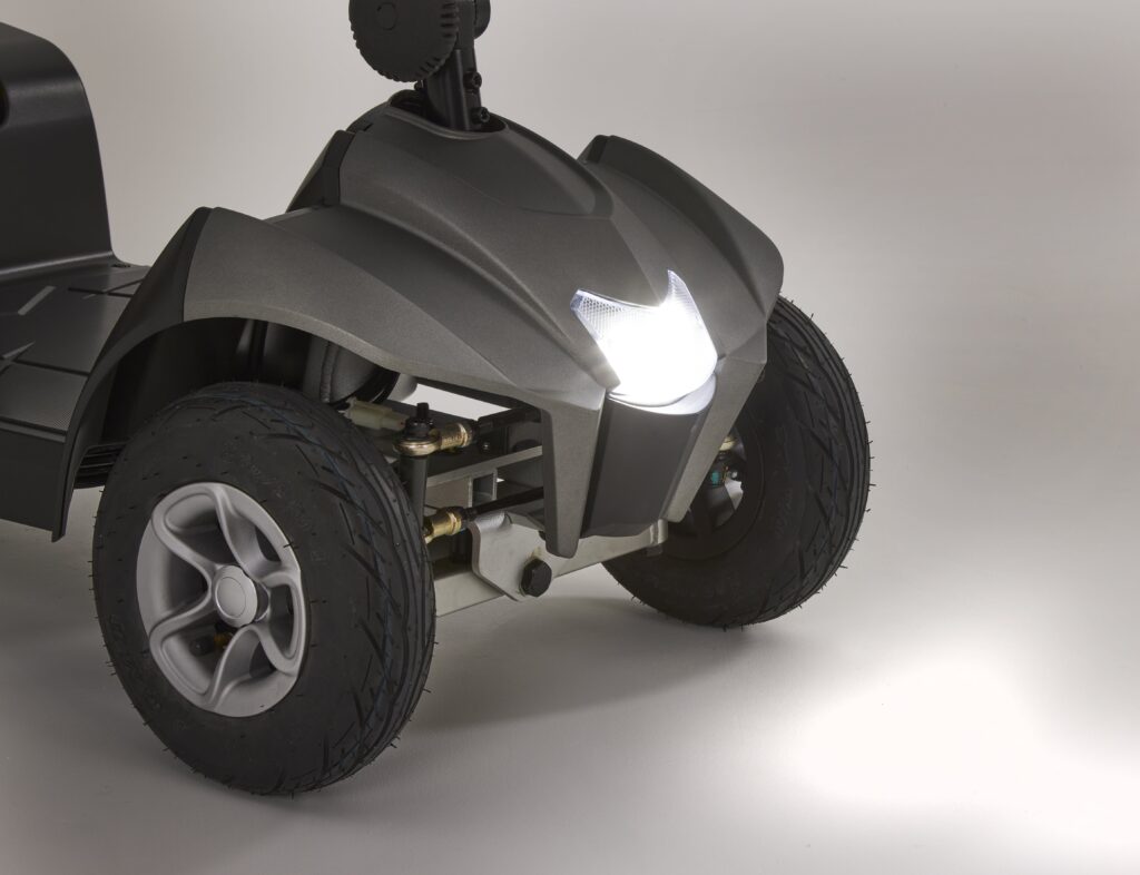Front view of the Eden Essential Aura 4mph boot mobility scooter with headlight turned on and large durable tires visible