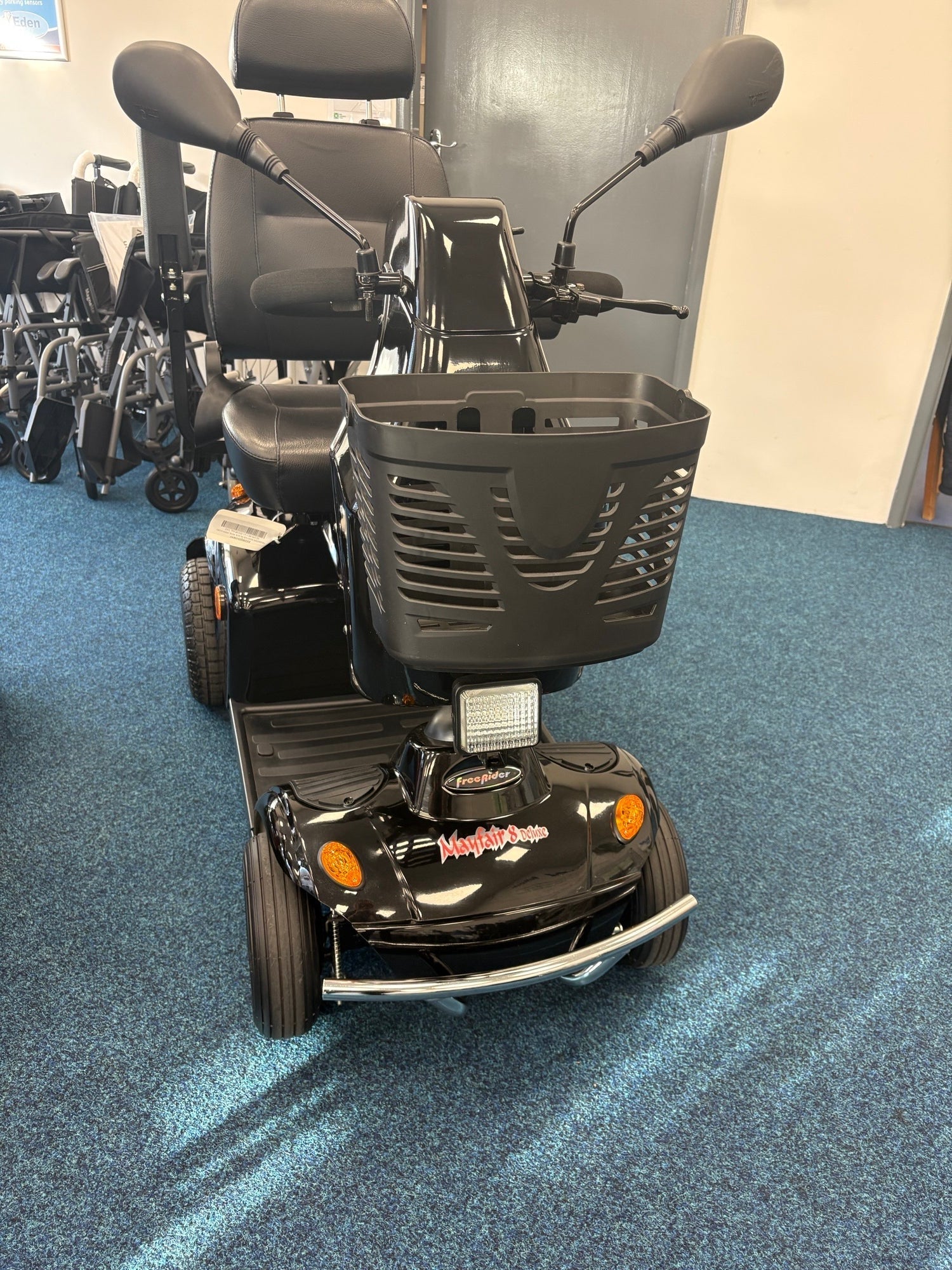 Black Freerider Mayfair mobility scooter with basket and padded seat on blue carpet indoors