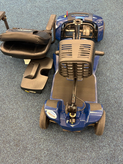 Disassembled Pride Apex Lite Blue mobility scooter with seat and battery pack on blue carpeted floor