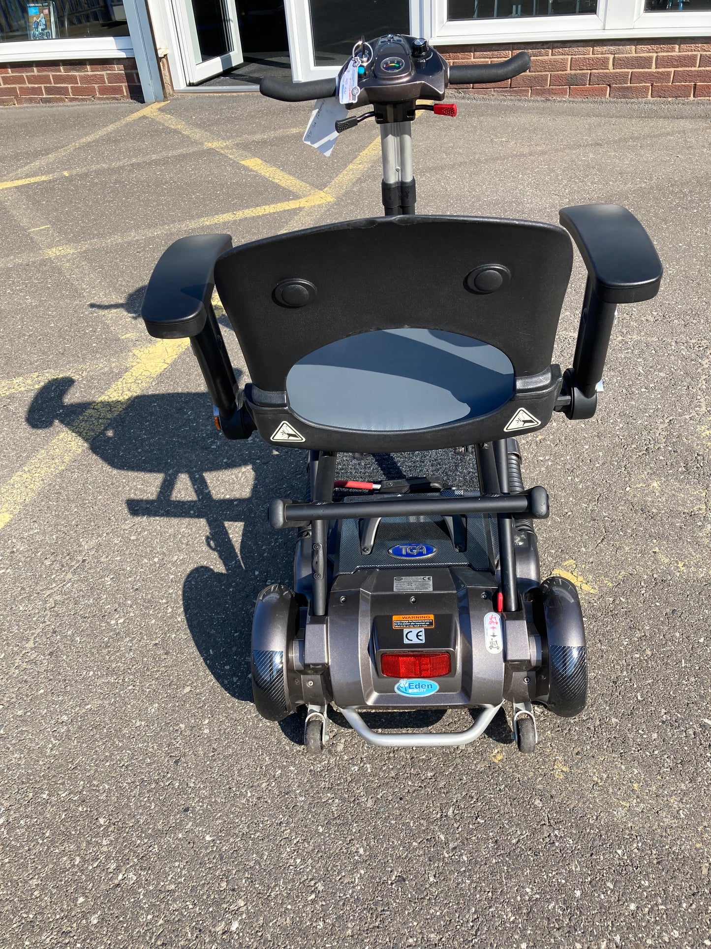 Back view of TGA Minimo - Bronze mobility scooter on a paved surface.