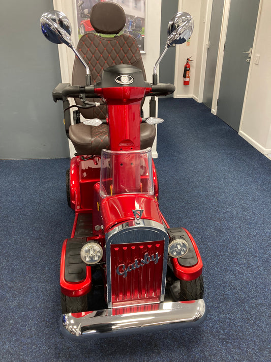 Red Eden Gatsby mobility scooter with brown quilted seat, armrests, and rearview mirrors on blue carpet indoors