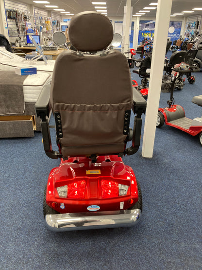 Rear view of red Eden Gatsby mobility scooter with brown seat inside mobility store on blue carpet floor