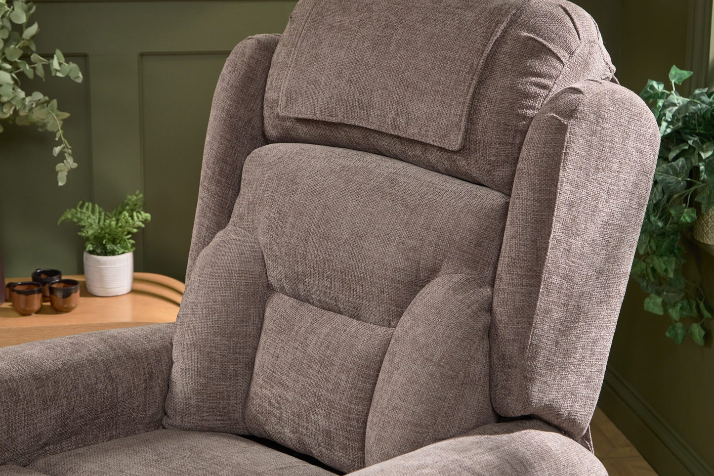 Close-up of a brown Monterey Rise & Recliner chair with padded support and soft fabric upholstery in a cozy room setting