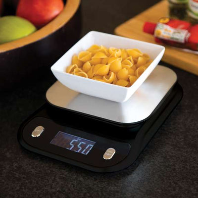 Digital kitchen scale with a bowl of pasta on a dark surface