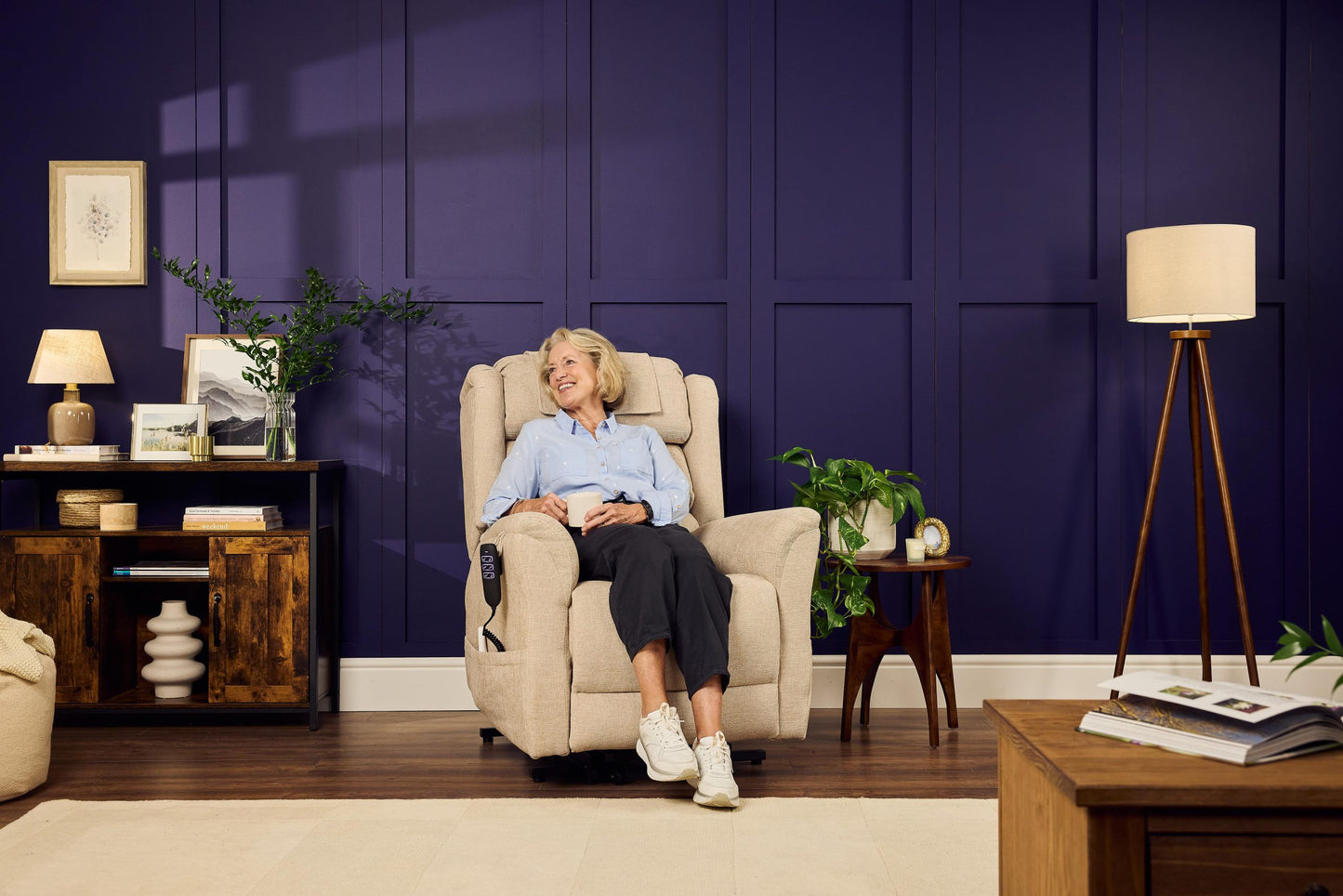 Woman sitting comfortably in a cream Sanford Rise and Recliner with dual motor recline in a modern living room