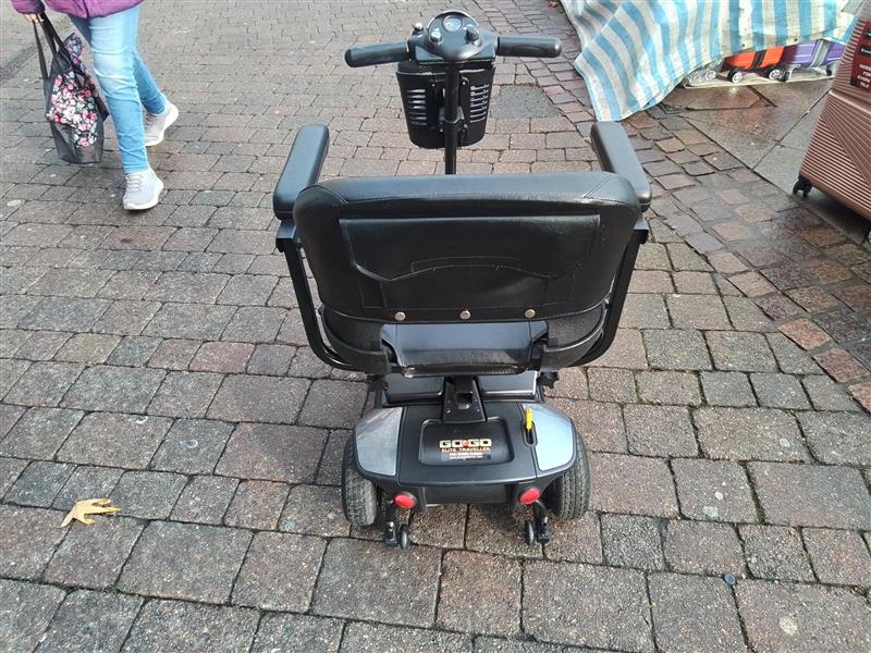 Rear view of a refurbished grey Pride Go Go Elite Traveller mobility scooter on a paved outdoor surface