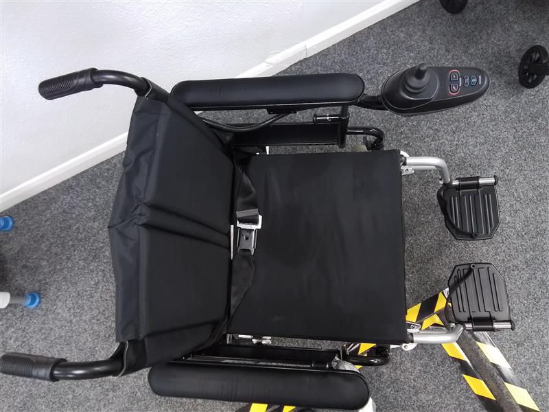 Top view of black Drive Cirrus powerchair with joystick control and padded seat on gray carpeted floor