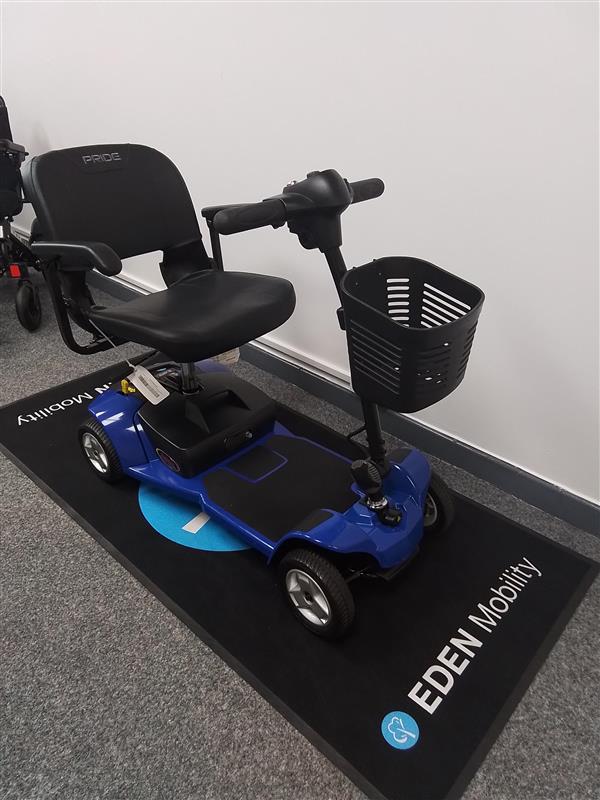 Refurbished Pride Apex Lite Blue mobility scooter with comfortable seat and front storage basket on display mat.