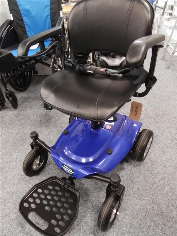Purple Careco Fenix powerchair with black seat, armrests, joystick control, and footrest on gray indoor floor