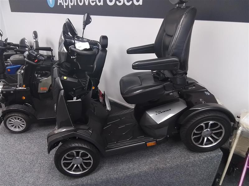 Grey Drive King Cobra mobility scooter fully refurbished with leather seat and alloy wheels, shown in showroom setting.