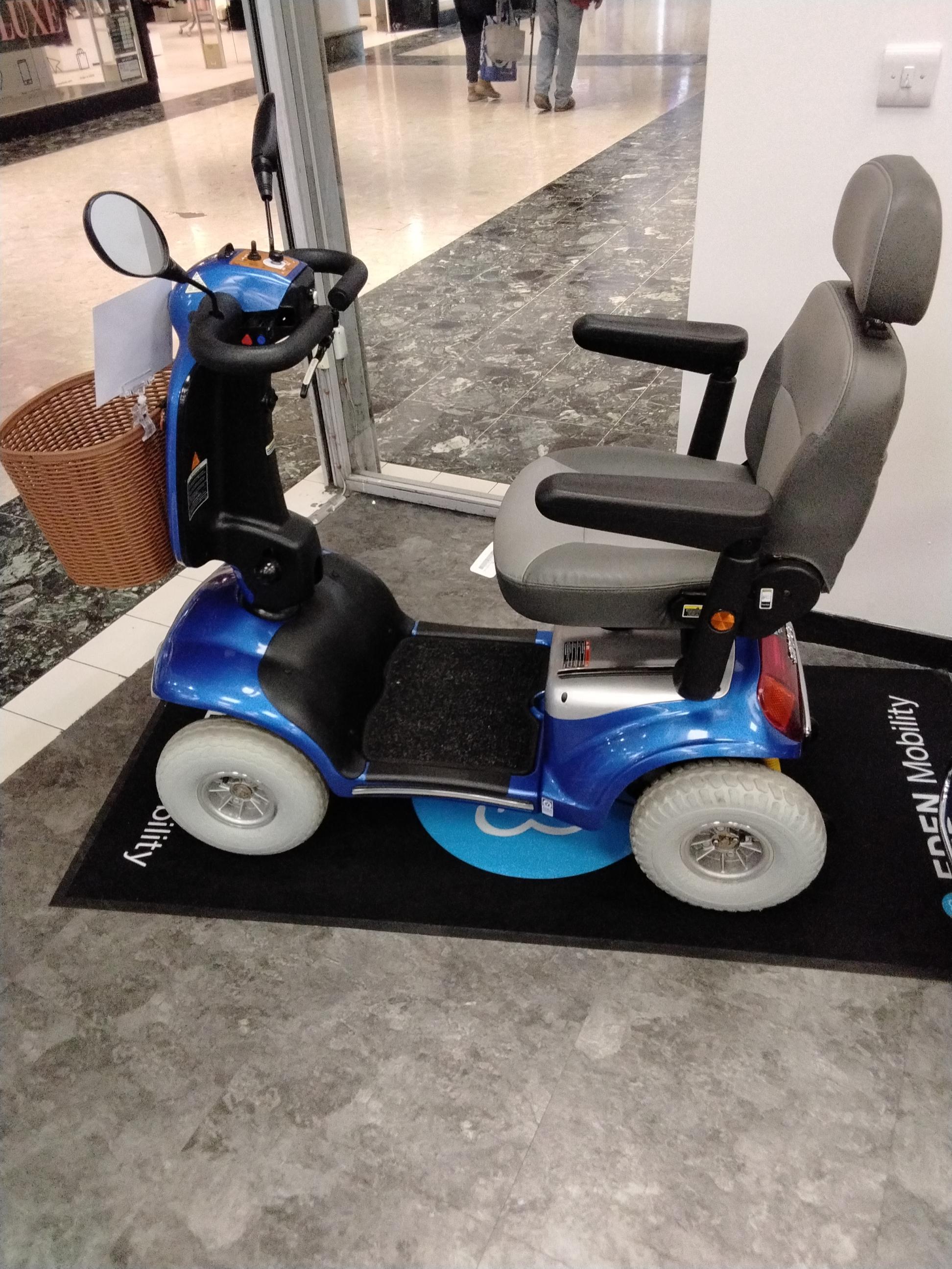 Refurbished blue Roma Shoprider Cadiz mobility scooter with comfortable seat and rearview mirror in indoor shopping area