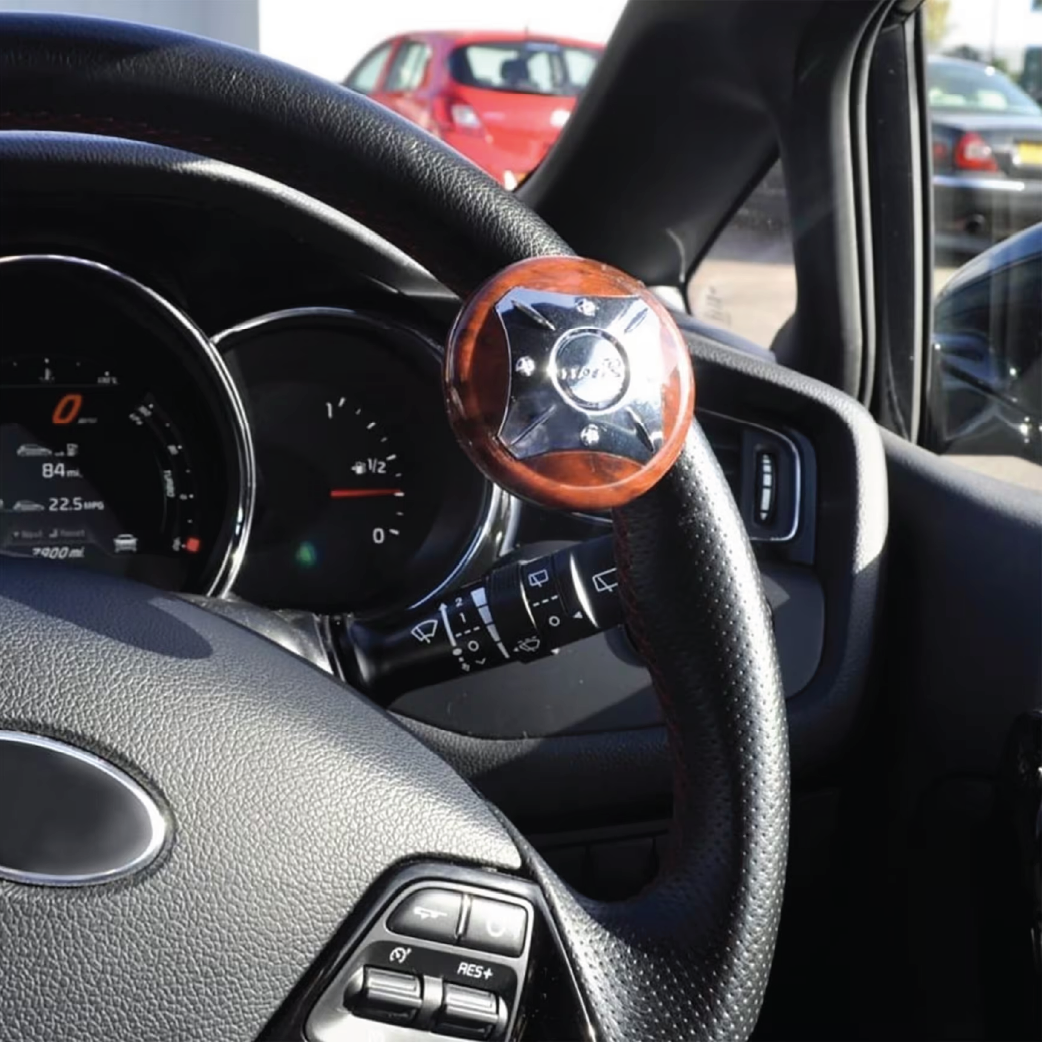 Steering wheel with attached Ezee Turn Steering Knob featuring polished wood and metal design in car interior