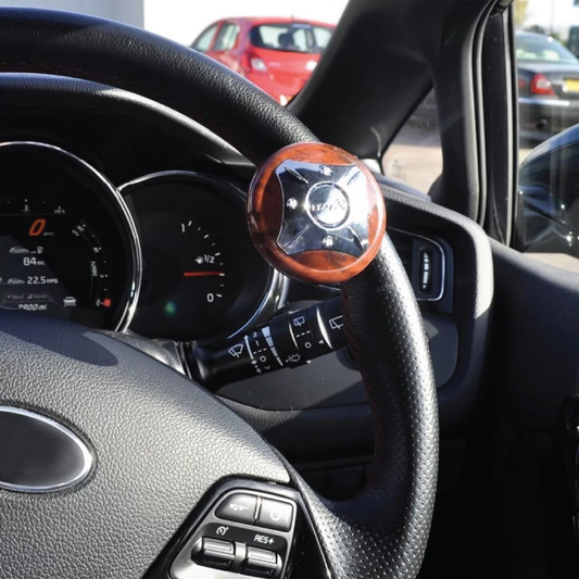 Steering wheel with attached Ezee Turn Steering Knob featuring polished wood and metal design in car interior