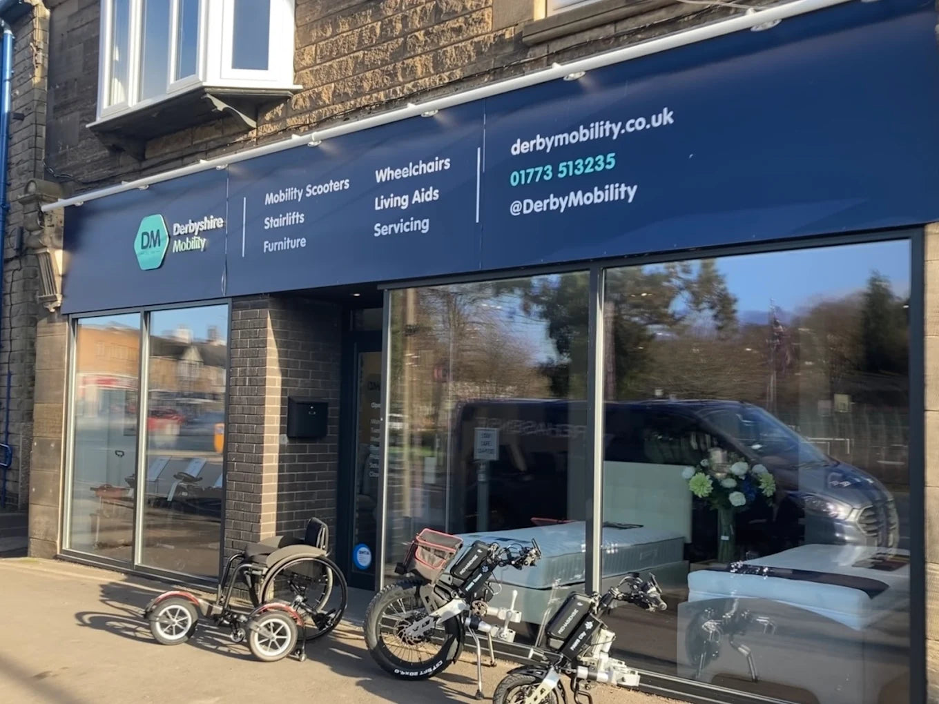 Exterior view of a mobility aid store with scooters and wheelchairs displayed outside on a sunny day.